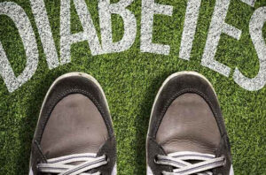 A pair of shoes next to the word 'diabetes' painted on grass